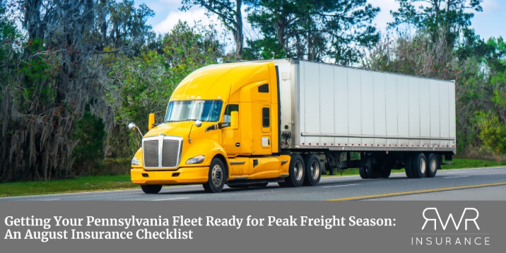 A yellow semi-truck with a white trailer drives down a paved road lined with trees, while a dark grey banner at the bottom contains the headline text, "Getting Your Pennsylvania Fleet Ready for Peak Freight Season: An August Insurance Checklist," alongside a white stylized logo and the text "RWR INSURANCE" in the bottom right corner. - www.rwrtruckinginsurance.com